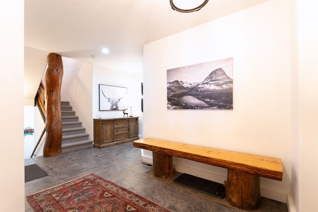 corridor featuring stairs and stone finish floors