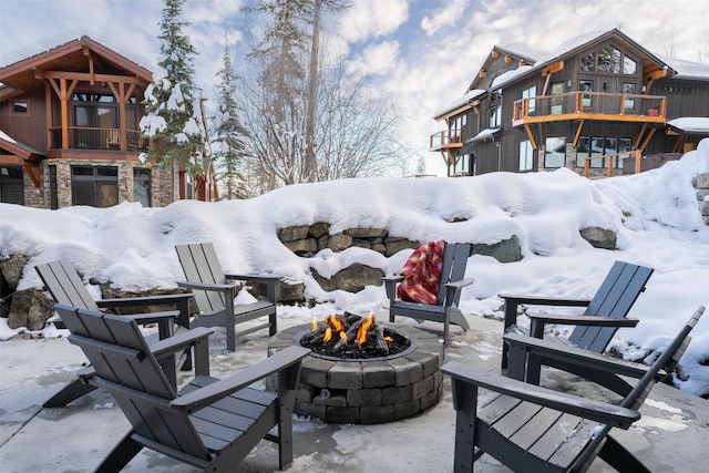 snow covered patio featuring an outdoor fire pit, a balcony, and a patio