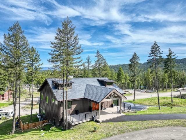 111 Blacktail Loop, Lakeside, MT 59922 - view of front facade with board and batten siding, a view of trees, a front yard, and covered porch