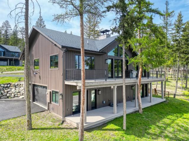 111 Blacktail Loop, Lakeside, MT 59922 - back of property with an attached garage, a patio, a lawn, roof with shingles, and a chimney