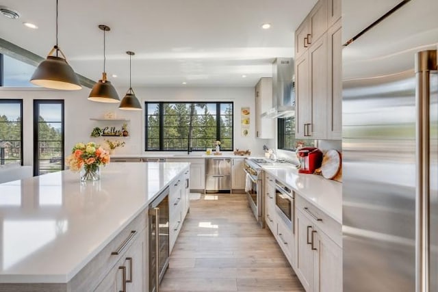 111 Blacktail Loop, Lakeside, MT 59922 - kitchen with high end appliances, wall chimney range hood, wine cooler, light wood-style flooring, and light countertops