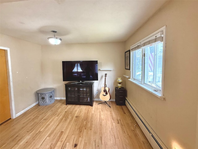 unfurnished living room featuring baseboard heating, wood finished floors, and baseboards
