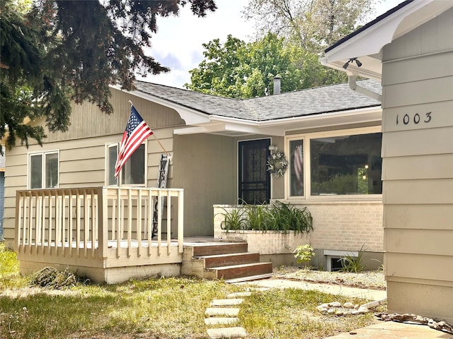 entrance to property with roof with shingles and a wooden deck