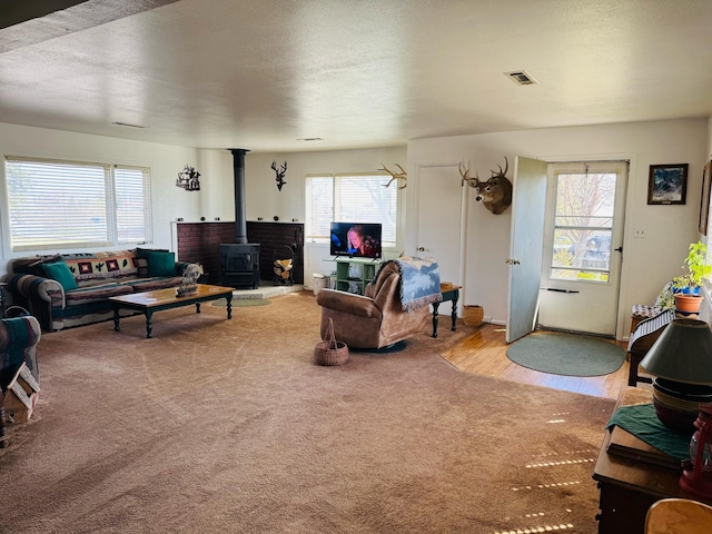 901 Birch Ave, Shelby, MT 59474 - carpeted living area featuring a wood stove, a textured ceiling, and wood finished floors