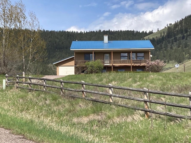 42984 Flathead View Dr, Polson, MT 59860 - view of front of property featuring a forest view, fence, a chimney, metal roof, and covered porch