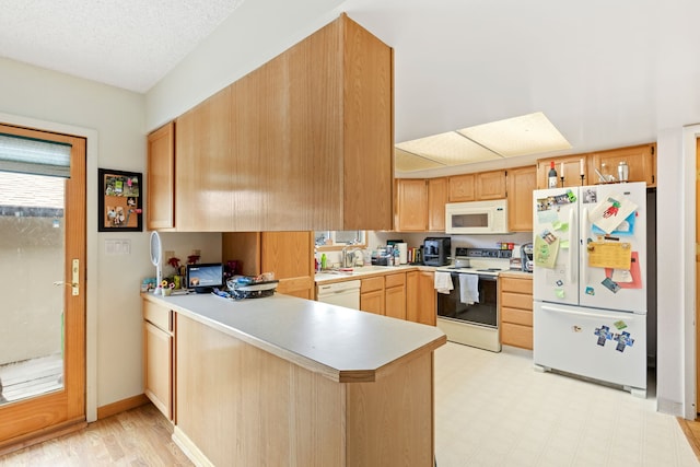 1200 32nd St S Unit 6, Great Falls, MT 59405 - kitchen with white appliances, a peninsula, light countertops, light brown cabinetry, and a sink