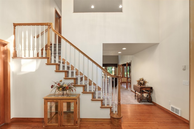 stairs with wood finished floors, baseboards, and a towering ceiling