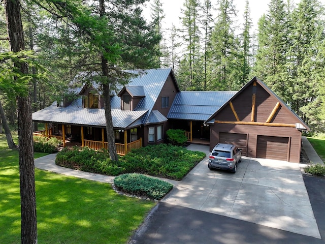view of front of home featuring concrete driveway, a front yard, a garage, a porch, and metal roof