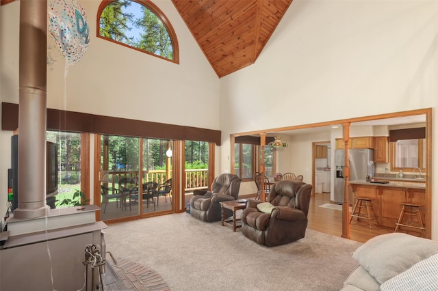 living area with high vaulted ceiling, wooden ceiling, and light colored carpet