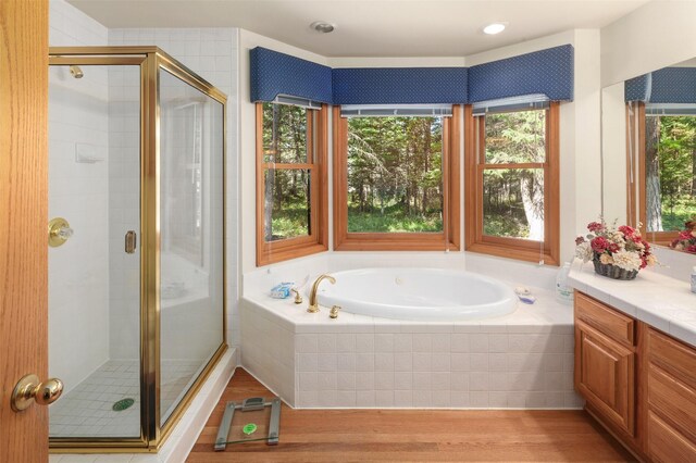 bathroom featuring a bath, a shower stall, wood finished floors, and healthy amount of natural light