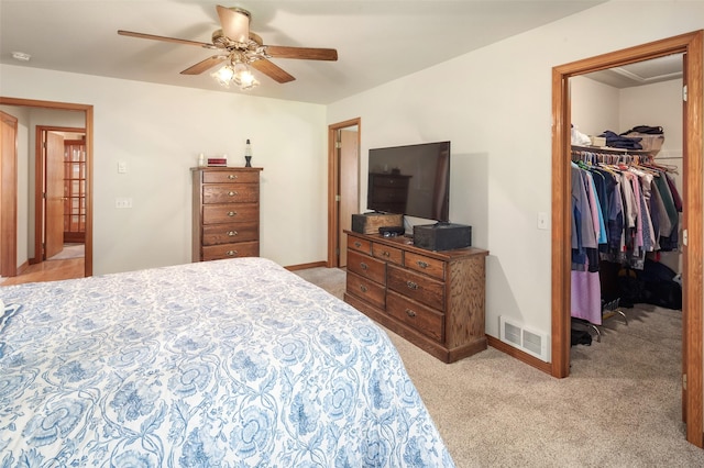 bedroom featuring light carpet, a spacious closet, and baseboards