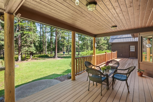 wooden terrace featuring a lawn and view of wooded area