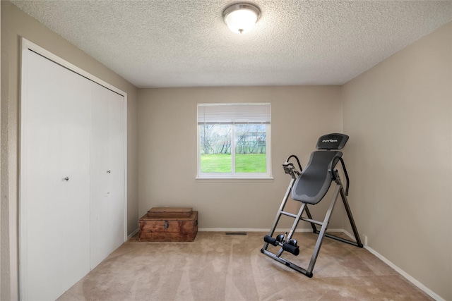exercise room featuring a textured ceiling, carpet, and baseboards