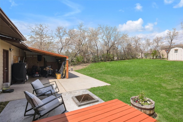 view of green lawn with an outdoor fire pit, a patio, a shed, and an outbuilding