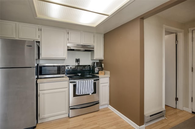 kitchen with appliances with stainless steel finishes, under cabinet range hood, light wood-type flooring, a baseboard heating unit, and light countertops