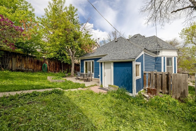 rear view of house featuring a shingled roof and a patio area
