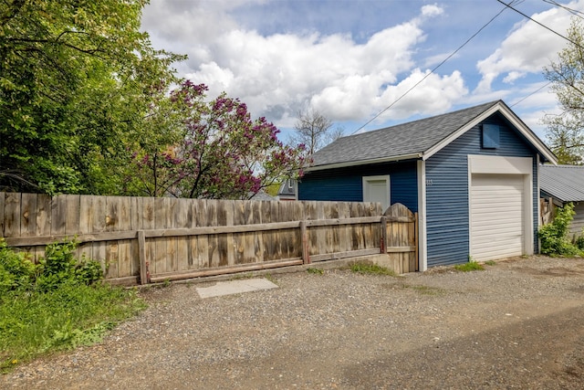 detached garage with fence and dirt driveway