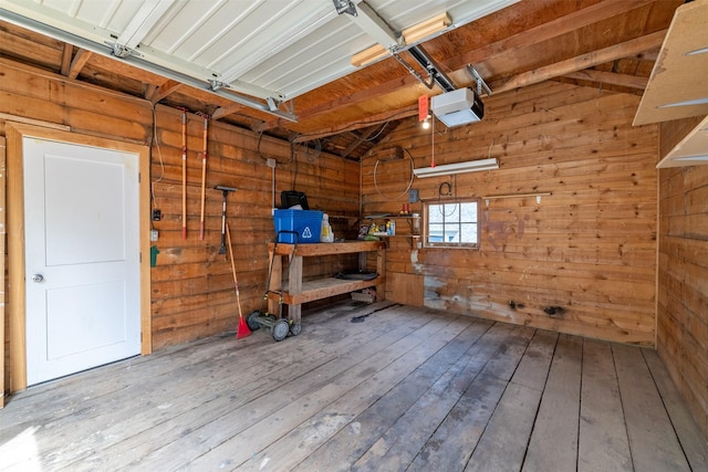 garage featuring a garage door opener, a workshop area, and wooden walls