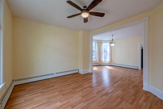 spare room with a baseboard heating unit, light wood-type flooring, ceiling fan, and baseboards