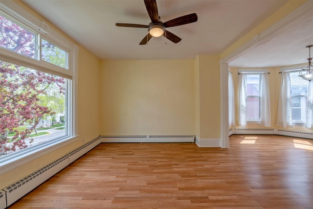 empty room featuring healthy amount of natural light, a baseboard radiator, and light wood-type flooring