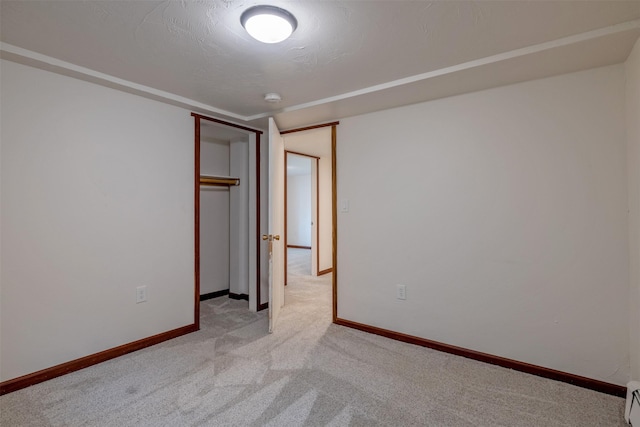 unfurnished bedroom with light carpet, baseboards, a baseboard heating unit, and a closet