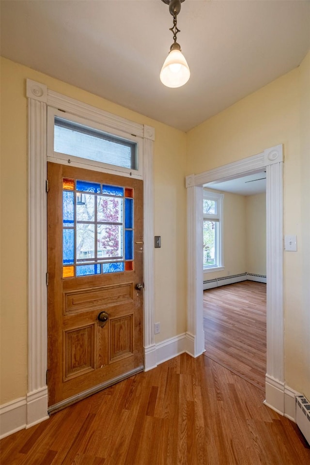 entryway featuring wood finished floors, a baseboard radiator, and baseboards