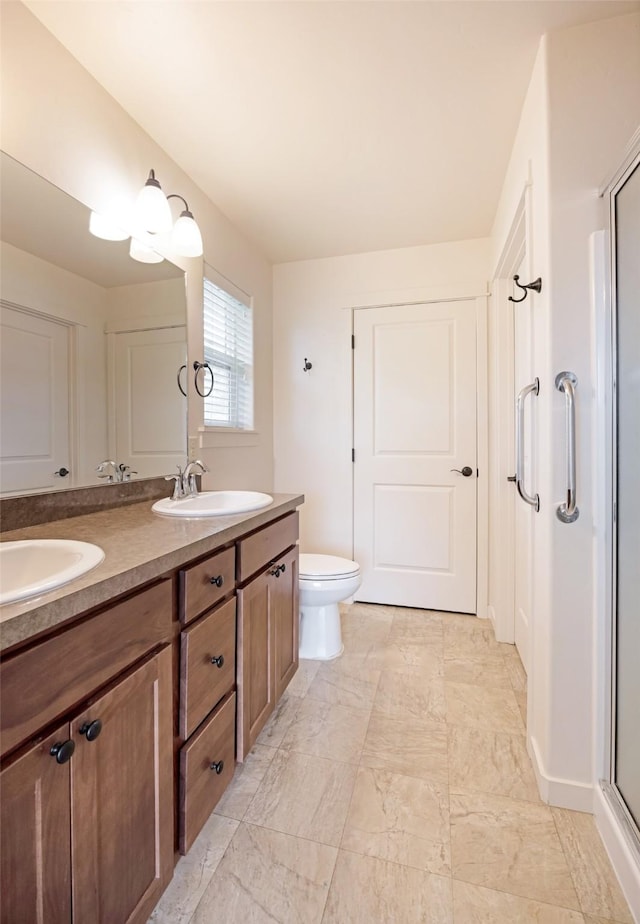 full bath featuring a shower stall, double vanity, toilet, and baseboards