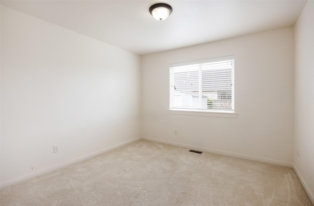 empty room featuring light carpet and baseboards