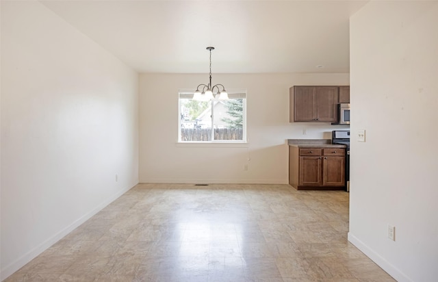 unfurnished dining area with a chandelier and baseboards