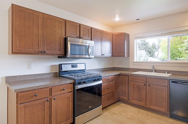 kitchen featuring stainless steel appliances, a sink, brown cabinets, and recessed lighting