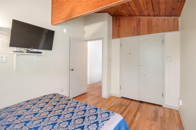 bedroom with light wood-style flooring, wood ceiling, baseboards, and a closet