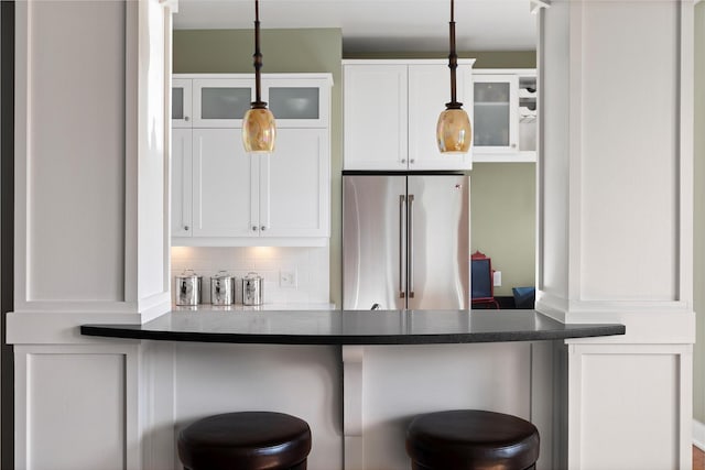 432 W Spruce St Unit 202, Missoula, MT 59802 - kitchen with high end refrigerator, white cabinets, a kitchen breakfast bar, glass insert cabinets, and hanging light fixtures