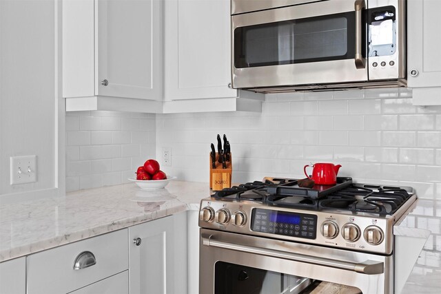 432 W Spruce St Unit 202, Missoula, MT 59802 - kitchen featuring appliances with stainless steel finishes, white cabinetry, backsplash, and light stone counters