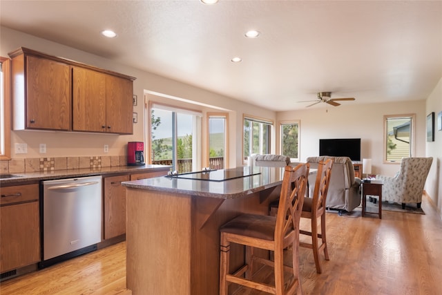 5190 Goodan Ln, Missoula, MT 59808 - kitchen featuring stainless steel dishwasher, black electric stovetop, light wood-style flooring, a breakfast bar area, and a kitchen island