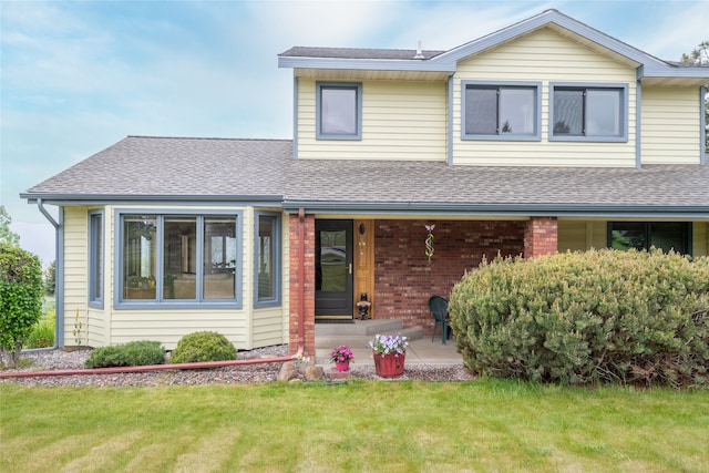5190 Goodan Ln, Missoula, MT 59808 - view of front of home featuring a shingled roof, a front yard, covered porch, and brick siding