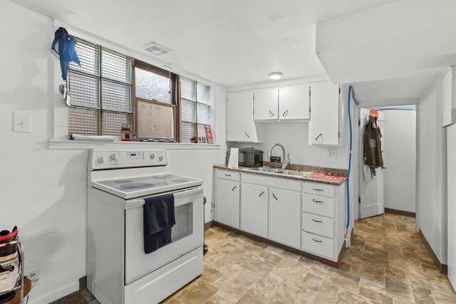 kitchen featuring electric range, a sink, white cabinetry, baseboards, and stone finish floors