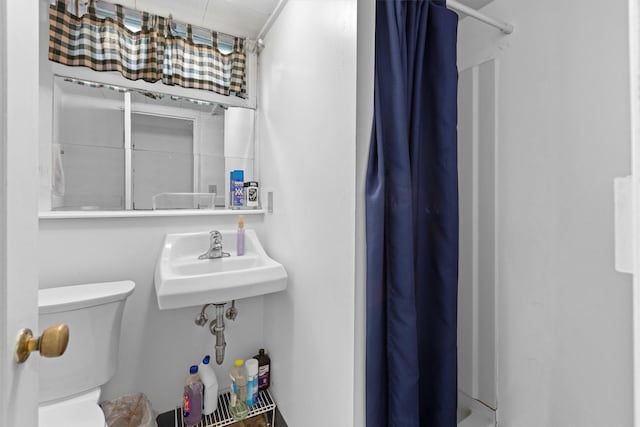 bathroom with a shower with curtain, toilet, and a sink