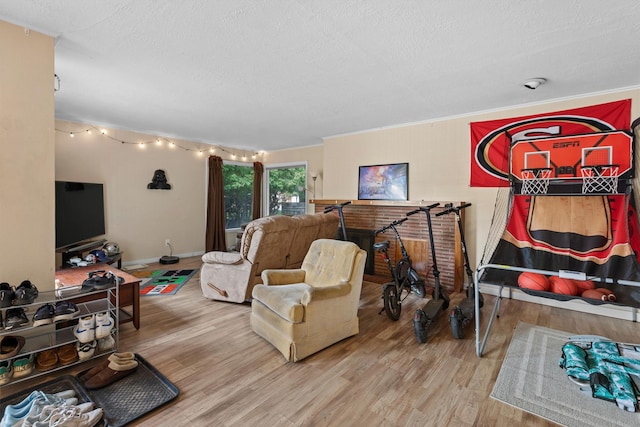 living area with wood finished floors, a textured ceiling, baseboards, and ornamental molding