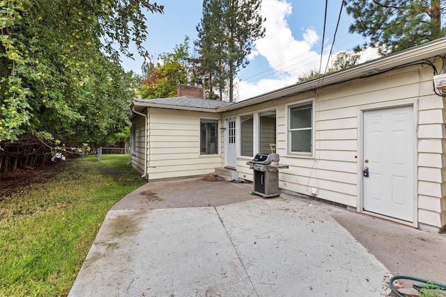 rear view of house with a patio area, a chimney, and a yard