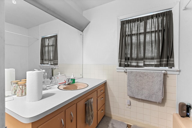 bathroom featuring tile walls, double vanity, and a wainscoted wall