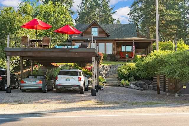 15222 Mt Highway 35, Bigfork, MT 59911 - log cabin featuring stairs, driveway, a shingled roof, and a carport