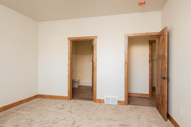 unfurnished bedroom featuring carpet, baseboards, and ensuite bathroom