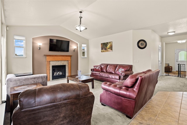 2719 Carnoustie Way, Missoula, MT 59808 - living area featuring light carpet, arched walkways, a tile fireplace, lofted ceiling, and plenty of natural light