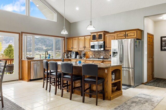 207 Cyprus Dr, Butte, MT 59701 - kitchen featuring stainless steel appliances, stone countertops, brown cabinetry, tasteful backsplash, and high vaulted ceiling