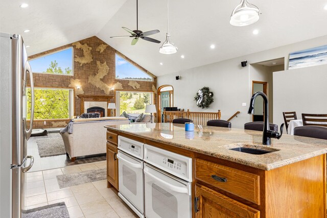 207 Cyprus Dr, Butte, MT 59701 - kitchen featuring freestanding refrigerator, a sink, open floor plan, a warm lit fireplace, and high vaulted ceiling
