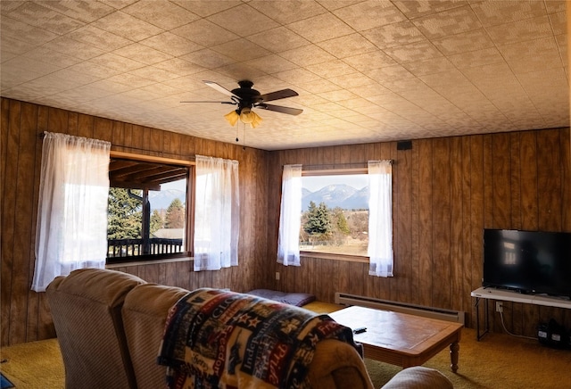 1807 1st St E, Polson, MT 59860 - living area with a baseboard heating unit, carpet floors, plenty of natural light, ceiling fan, and wood walls