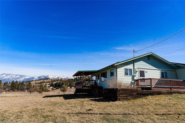 1807 1st St E, Polson, MT 59860 - view of home's exterior with a deck with mountain view, a yard, and stairway