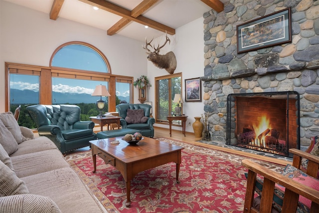 215 Somerset Dr, Kalispell, MT 59901 - living area featuring beamed ceiling, a stone fireplace, wood finished floors, plenty of natural light, and a high ceiling