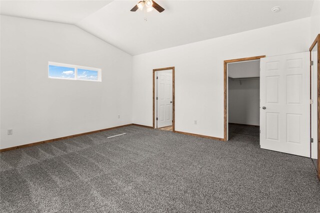 4452 Ludwig Ln, Stevensville, MT 59870 - unfurnished bedroom with vaulted ceiling, dark colored carpet, a walk in closet, baseboards, and ceiling fan