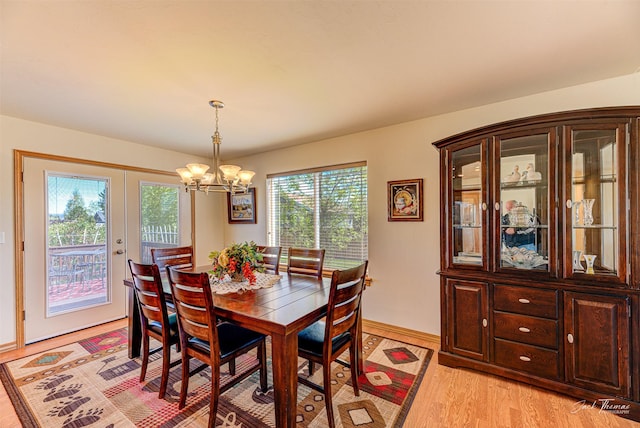 dining room featuring a chandelier, light wood-type flooring, baseboards, and french doors